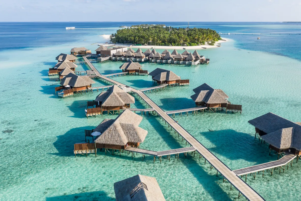 Overwater villas and a tropical island above a clear turquoise lagoon